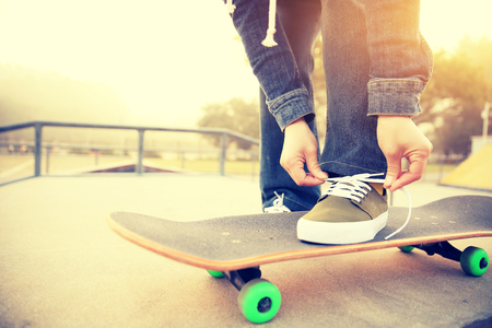skateboarder tying shoelace  at skatepark rampの写真素材