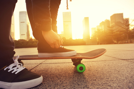 skateboarder tying shoelace at cityの写真素材