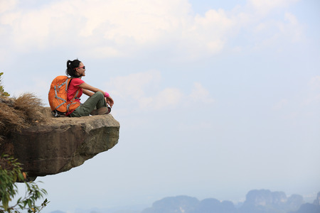 successful woman hiker  enjoy the view at mountain peak cliffの写真素材