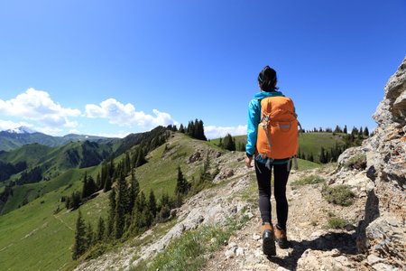 young woman backpacker hiking on beautiful mountain peak trail