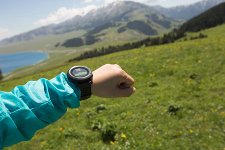 young woman hiker checking the altimeter on sports watch at mountain peak