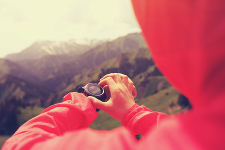 young woman hiker checking the altimeter on sports watch at mountain peakの写真素材