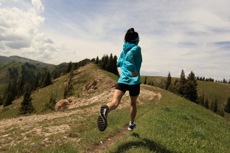 healthy young woman trail runner running on beautiful mountain peakの写真素材