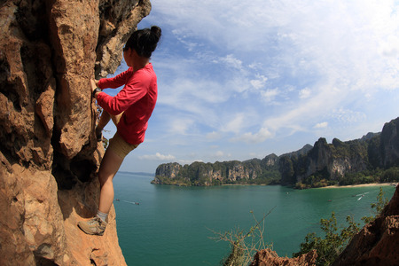 young woman rock climber climbing at seaside mountain cliff rockの写真素材