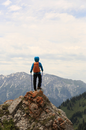 successful woman backpacker hiking on mountain peak cliffの写真素材