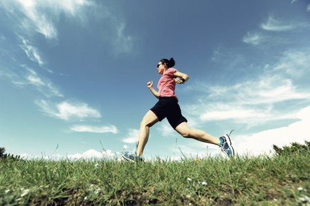 healthy young woman trail runner running on beautiful mountain peak
