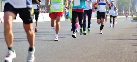 Unidentified marathon athletes legs running on city roadの写真素材