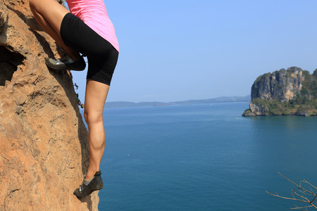 young woman rock climber climbing at seaside mountain cliffの写真素材