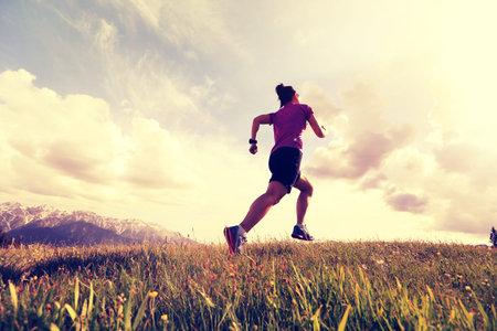 healthy young woman trail runner running on mountain peakの写真素材