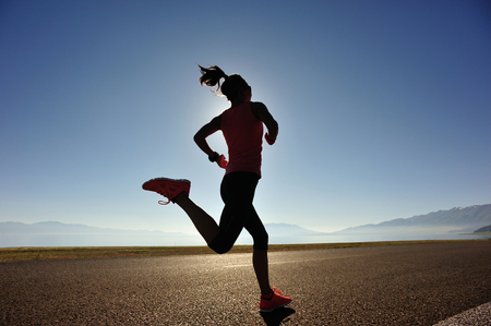 healthy lifestyle young woman runner running on sunrise seasideの写真素材