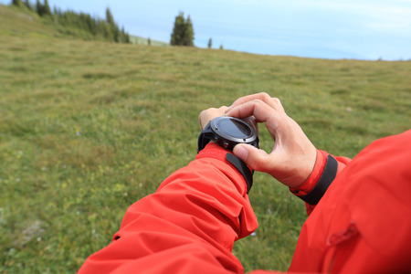 young woman hiker checking the altimeter on sports watch at mountain peakの写真素材