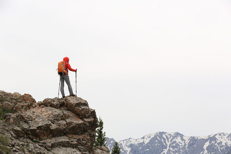 successful woman backpacker hiking  on mountain peak cliff