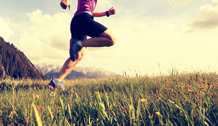 healthy young woman trail runner running on beautiful mountain peakの写真素材