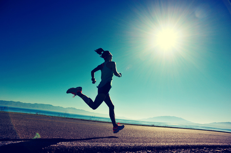 young fitness woman runner running on sunrise seaside trailの写真素材