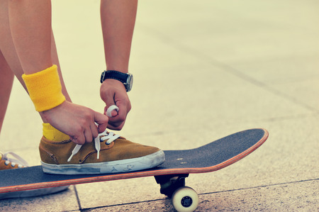 skateboarder tying shoelace at cityの写真素材