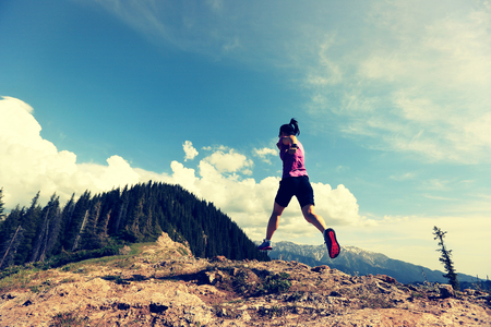 healthy lifestyle young woman trail runner running on beautiful mountain peakの写真素材