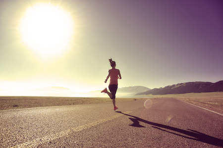 young fitness woman runner running on sunrise seaside trailの写真素材