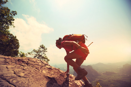 young asian woman hiker climbing rock on mountain peak cliffの写真素材
