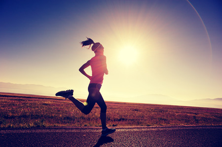 young fitness woman runner running on sunrise seaside trailの写真素材