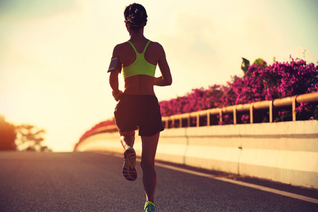 young woman runner running on city roadの写真素材