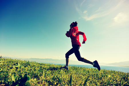 fitness young woman trail runner running on beautiful mountain peakの写真素材