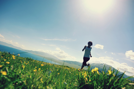 fitness young woman trail runner running on beautiful mountain peakの写真素材