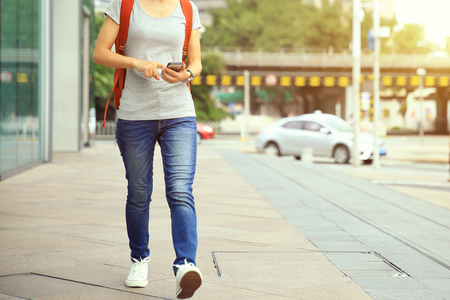 young woman walking with smart phone in modern cityの写真素材
