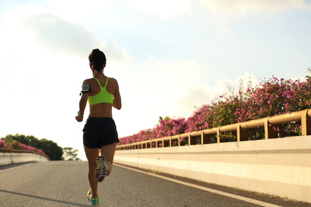young fitness woman runner running on city roadの写真素材
