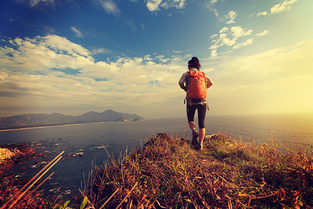 successful hiker walking on seaside mountain peakの写真素材
