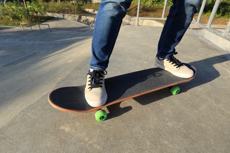 young skateboarder legs riding skateboard at skateparkの写真素材