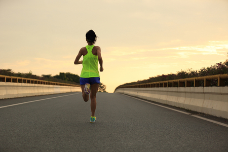 young fitness woman runner running on city roadの写真素材