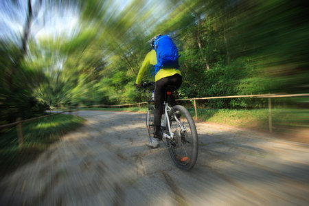 young woman riding mountain bike on forest trail