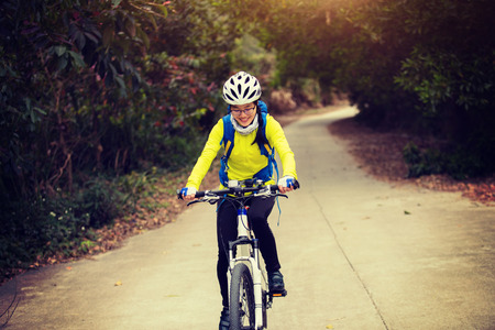 young woman riding mountain bike on forest trailの写真素材