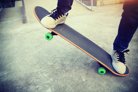 young skateboarder legs riding skateboard at skateparkの写真素材