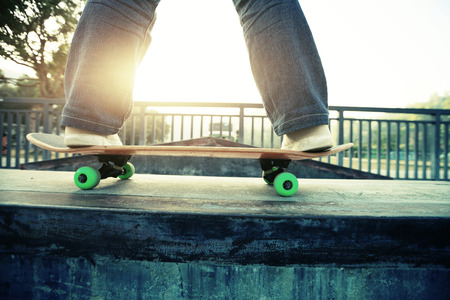 young skateboarder legs riding skateboard at skateparkの写真素材
