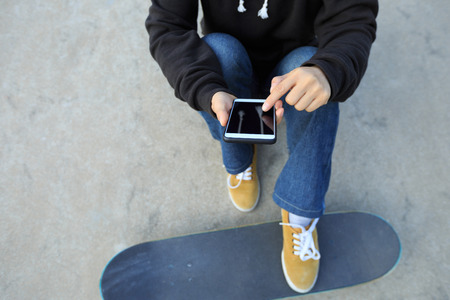 young skateboarder use cellphone  at skateparkの写真素材