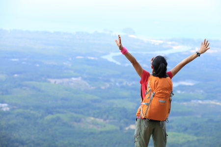 cheering young woman hiker at  mountain peakの写真素材