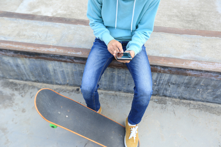 young skateboarder use cellphone  at skateparkの写真素材