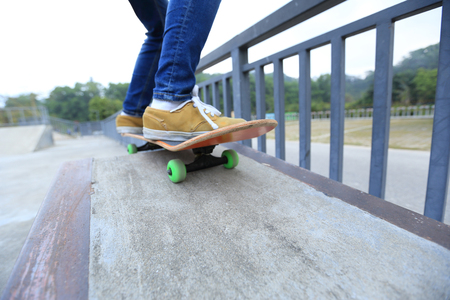 young skateboarder legs riding skateboard at skatepark rampの写真素材
