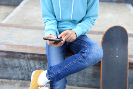 young skateboarder use cellphone  at skateparkの写真素材