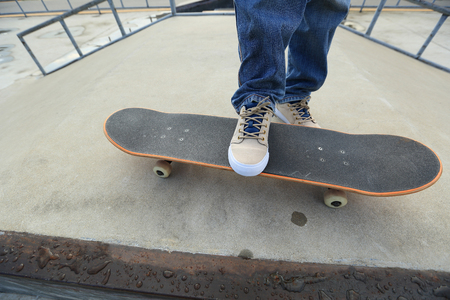 young skateboarder legs riding skateboard at skatepark rampの写真素材