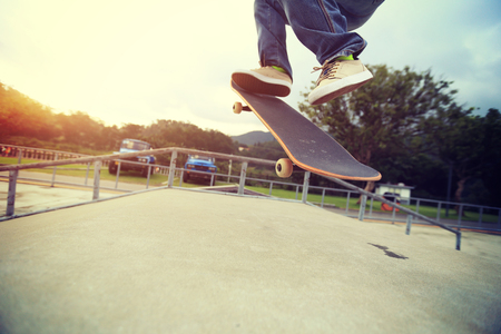 young skateboarder legs practice ollie at skatepark rampの写真素材