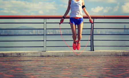 young fitness woman jumping rope at seasideの写真素材
