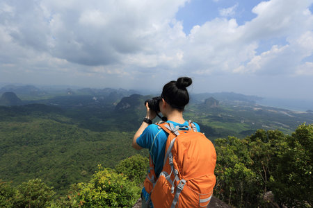 successful woman hiker taking photo hiking on mountain peak