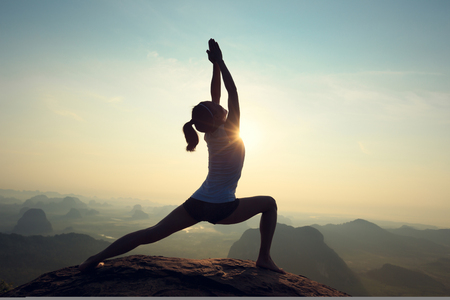 young fitness woman meditating on sunrise mountain peakの写真素材