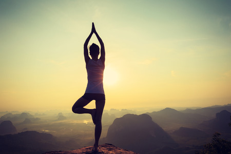young fitness woman meditating on sunrise mountain peakの写真素材
