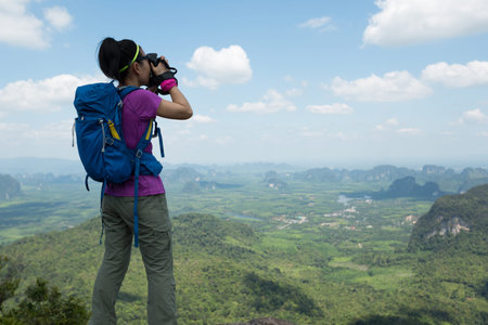 successful woman hiker taking photo hiking on mountain peakの写真素材