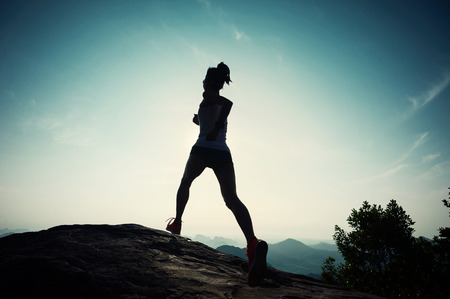 successful young woman running on sunrise mountain peakの写真素材