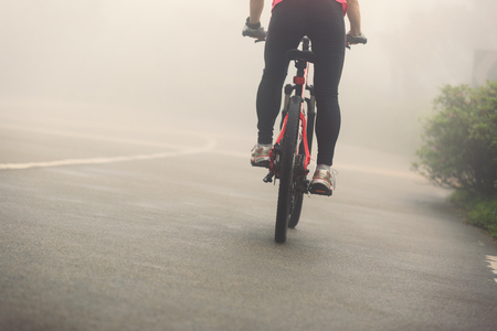 cyclist riding mountain bike on foggy forest trailの写真素材
