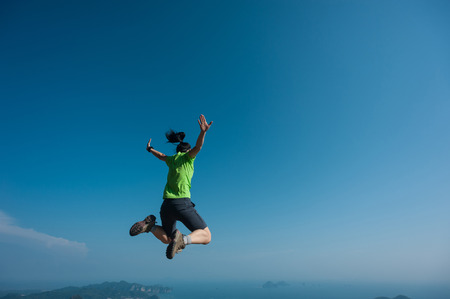 jumping on rocky mountain peak, freedom, risk, challenge, success conceptの写真素材